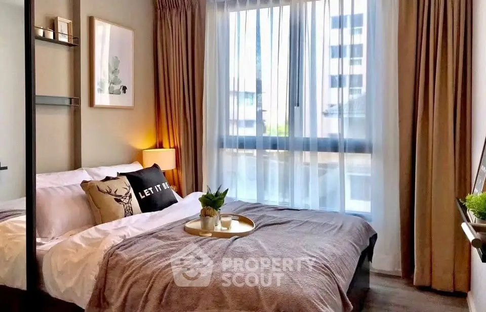 Cozy bedroom with modern decor and large window offering natural light.