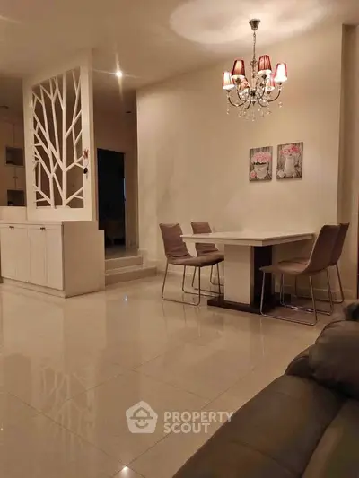 Elegant dining area with modern chandelier and artistic wall divider in a cozy home setting.