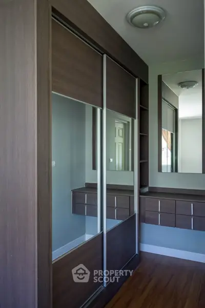 Modern bedroom with sleek wooden wardrobe and mirrored sliding doors