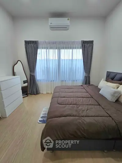 Cozy bedroom with large bed, elegant curtains, and modern air conditioning unit.