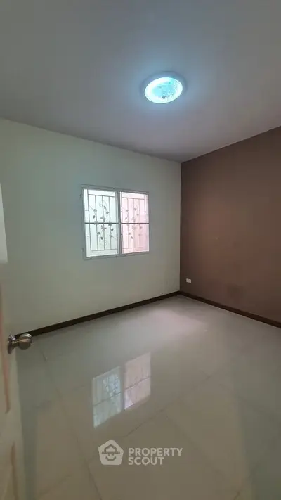 Spacious empty room with tiled flooring and window, perfect for customization.