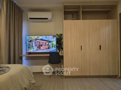 Modern bedroom with built-in wardrobe and wall-mounted TV, featuring stylish decor and air conditioning.