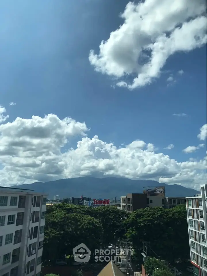 Stunning cityscape view with lush greenery and mountain backdrop under a vibrant blue sky.