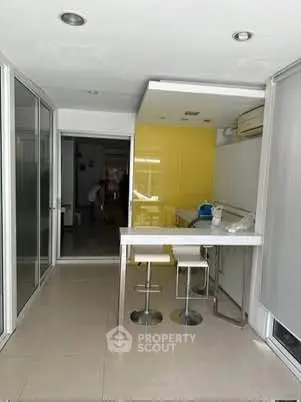 Modern kitchen with sleek design and bright yellow accent wall, featuring bar seating and contemporary lighting.