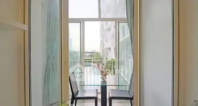 Charming balcony with pool view and cozy seating area in modern apartment.