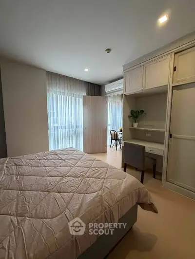 Modern bedroom with cozy decor and natural light, featuring a study nook and elegant furnishings.