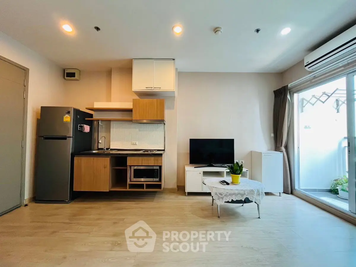 Modern open-layout living room with kitchen, featuring sleek appliances and natural light.