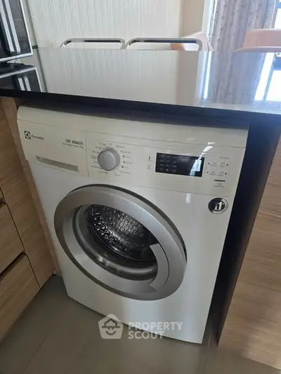 Modern kitchen with built-in Electrolux washing machine under sleek countertop.
