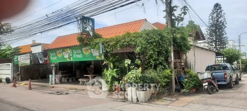 Charming street-side property with lush greenery and convenient parking, ideal for a cozy cafe or local business.