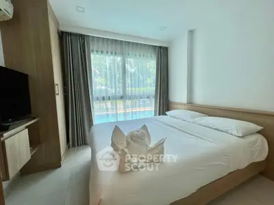 Cozy bedroom with pool view, featuring modern furnishings and natural light.