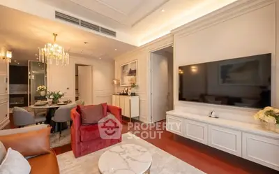 Luxurious living room with elegant decor and modern furnishings, featuring a large flat-screen TV and stylish chandelier.