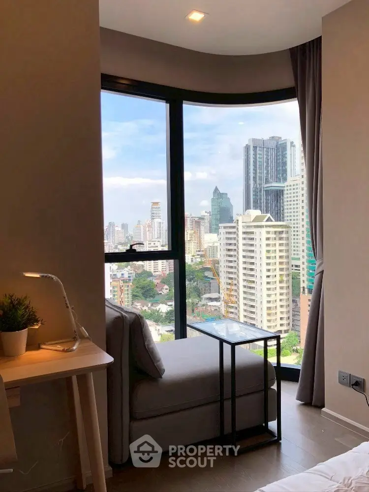 Modern apartment with stunning city view from large window, cozy seating area and stylish decor.