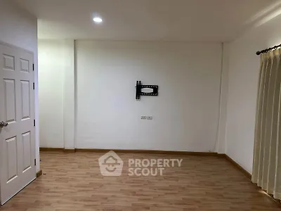 Spacious empty room with wooden flooring and wall mount for TV, ready for customization.