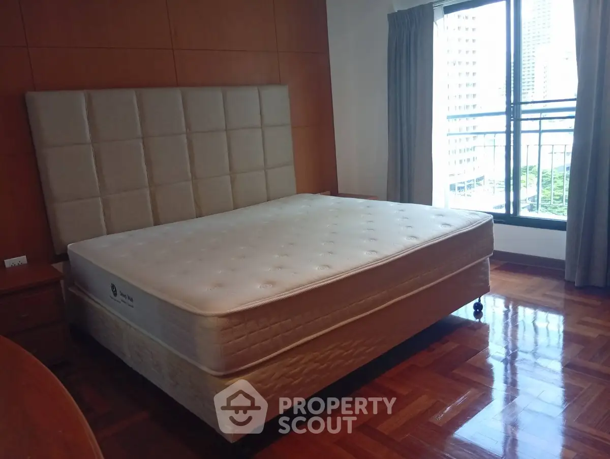 Spacious bedroom with large bed and city view from window