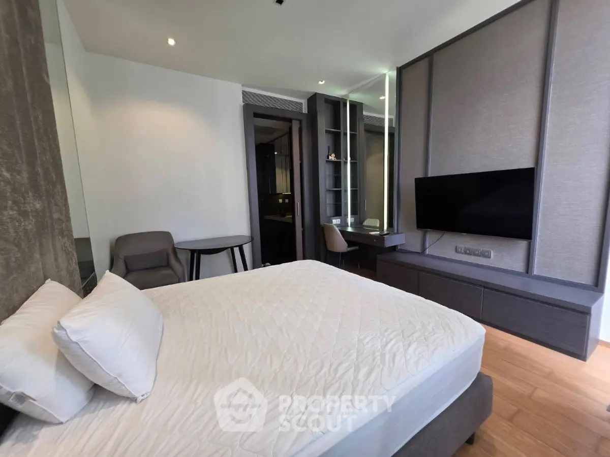 Modern bedroom with sleek furniture and wall-mounted TV in a stylish apartment.