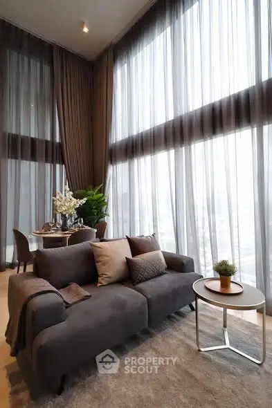 Luxurious high-ceiling living room with elegant decor and floor-to-ceiling windows.