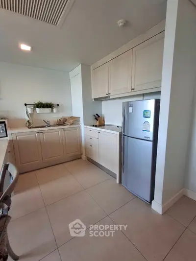 Modern kitchen with sleek cabinetry and stainless steel fridge in a cozy apartment.