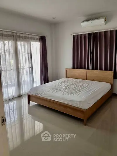 Spacious bedroom with large windows and modern air conditioning unit.