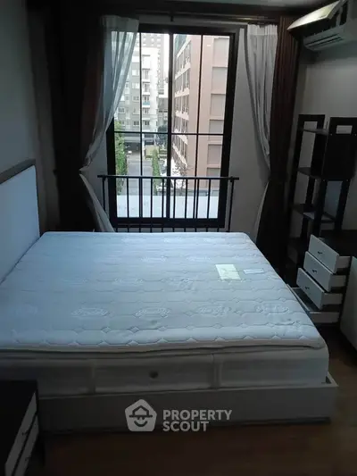 Cozy bedroom with large window and city view, featuring a comfortable bed and modern furniture.