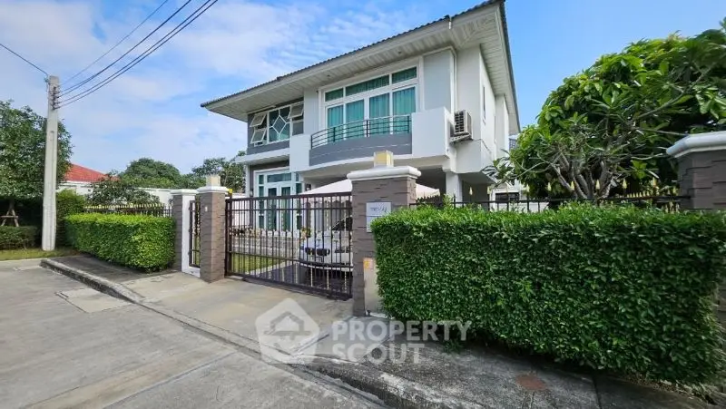 Stunning modern two-story house with lush greenery and gated entrance.