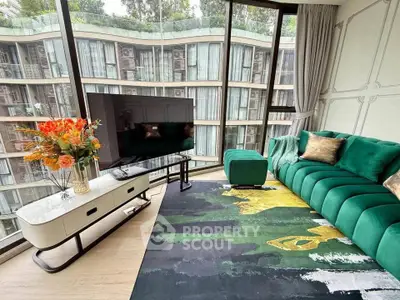 Luxurious living room with green sofa and floor-to-ceiling windows offering stunning views of modern architecture.