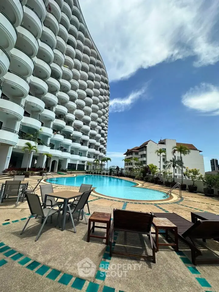 Luxurious apartment complex with stunning pool and modern architecture under clear blue sky.