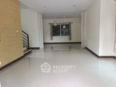 Spacious open-plan living area with modern staircase and large windows.