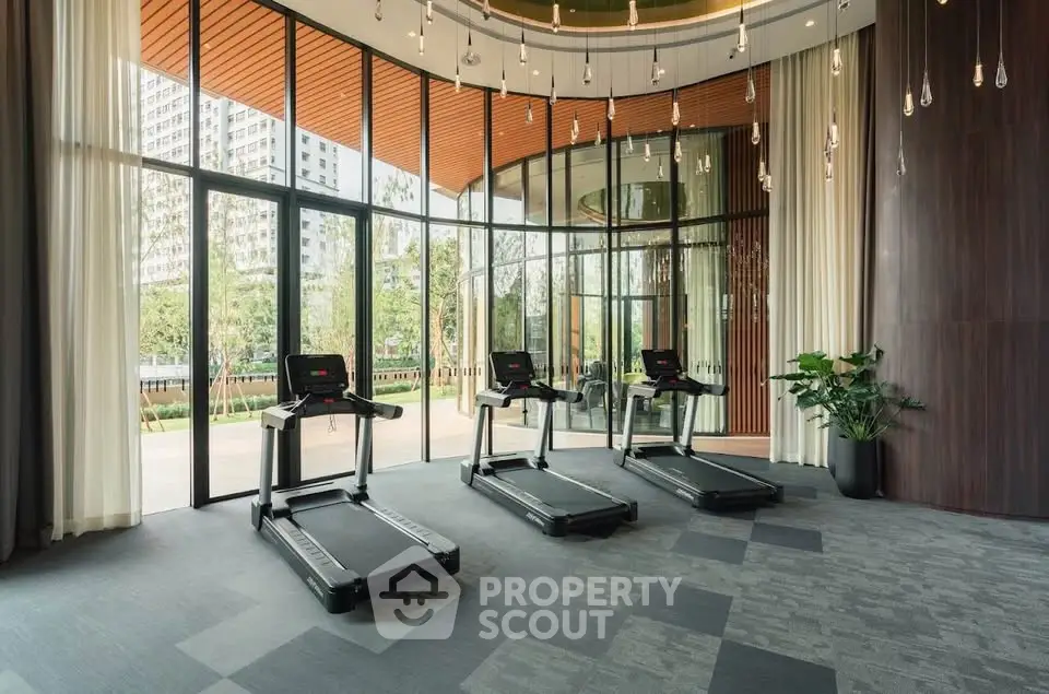 Modern gym with treadmills and floor-to-ceiling windows offering garden views