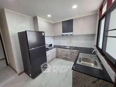 Modern kitchen with sleek cabinets, gas stove, and spacious fridge in a stylish apartment.