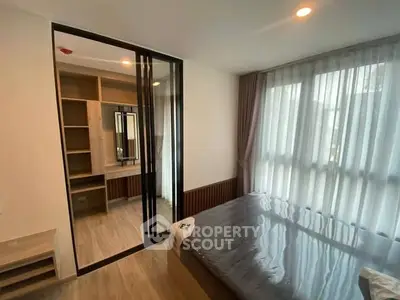 Modern bedroom with large window and stylish closet in a cozy apartment.