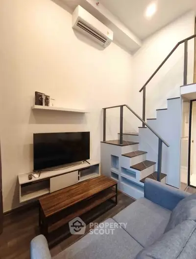 Modern living room with stylish staircase and sleek furniture design.