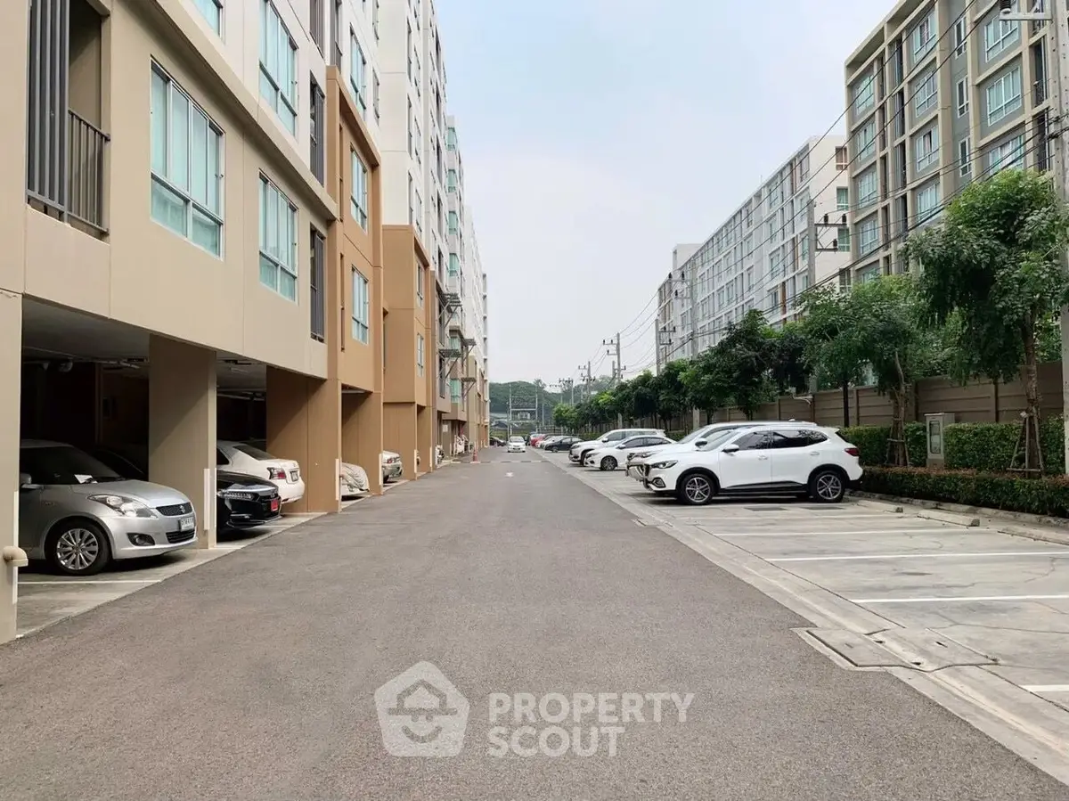 Modern apartment complex with spacious parking area and lush greenery.