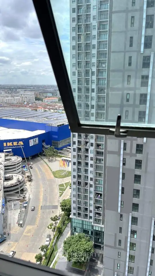Stunning cityscape view from high-rise apartment window near IKEA store.