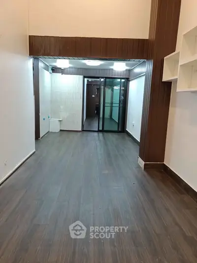 Spacious interior with wood flooring and glass partition, ideal for modern living or office space.