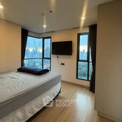Modern bedroom with city view and wall-mounted TV in high-rise apartment.
