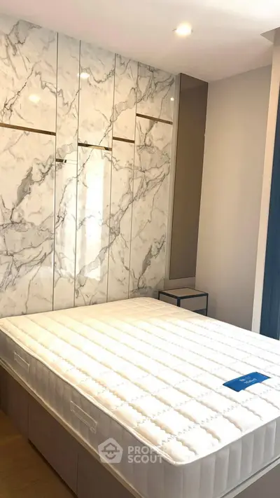 Modern bedroom with marble accent wall and comfortable mattress in stylish apartment.