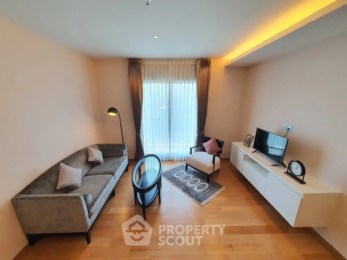Modern living room with stylish furniture and natural light, featuring a cozy seating area and sleek wooden flooring.