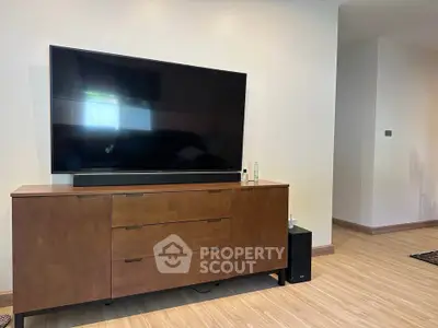 Modern living room with sleek wooden TV cabinet and large flat-screen TV