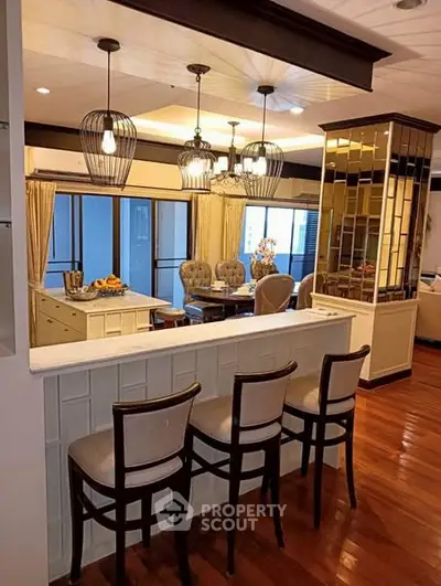 Elegant open-layout kitchen and dining area with stylish lighting and wooden flooring.