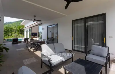 Luxurious outdoor patio with modern furniture and pool view in a tropical setting.