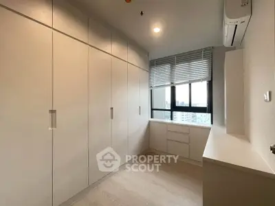 Spacious storage room with built-in cabinets and city view window