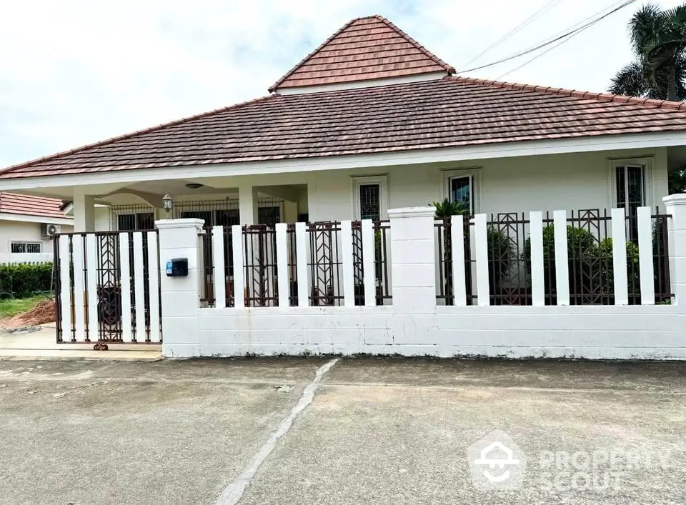 Charming single-story house with tiled roof and gated front yard in serene neighborhood.