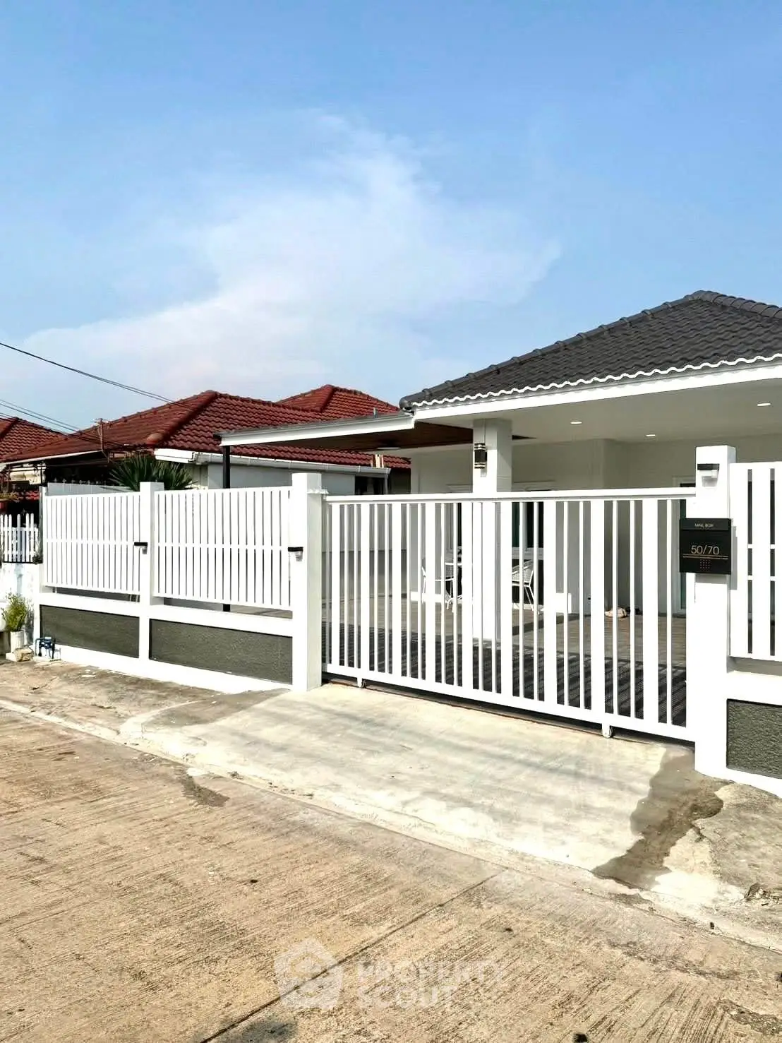 Charming single-story home with modern white fence and tiled roof in a serene neighborhood.