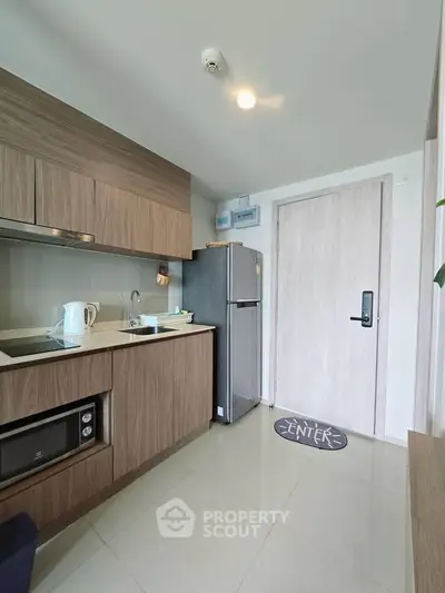 Modern kitchen with sleek wooden cabinets and stainless steel appliances in a cozy apartment.