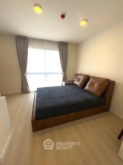 Modern bedroom with stylish leather bed and large window with curtains