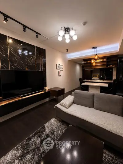 Modern living room with stylish decor and open dining area, featuring elegant lighting and sleek furniture.