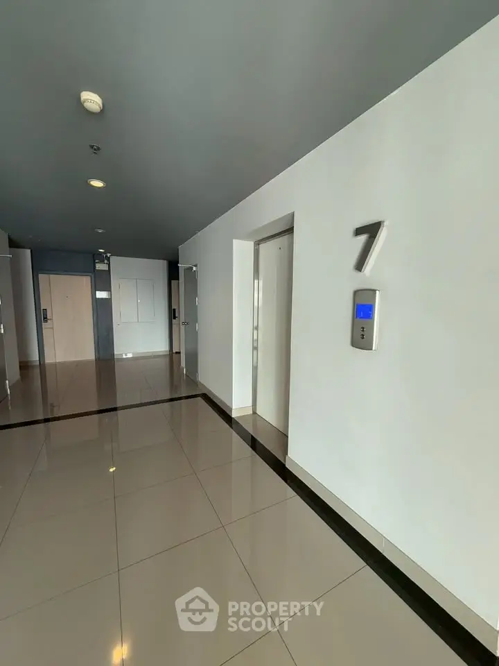 Modern building corridor with elevator access on the seventh floor, featuring sleek design and polished flooring.