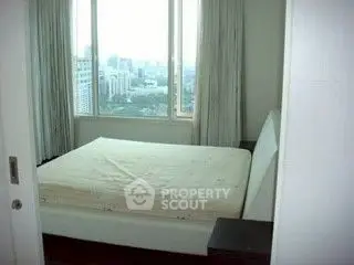 Cozy bedroom with city view from large window, perfect for urban living.