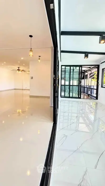 Spacious modern living area with sleek tile flooring and large windows for natural light.