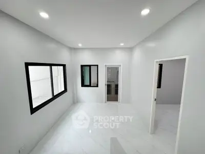 Modern minimalist interior with white walls and marble flooring, featuring large windows for natural light.